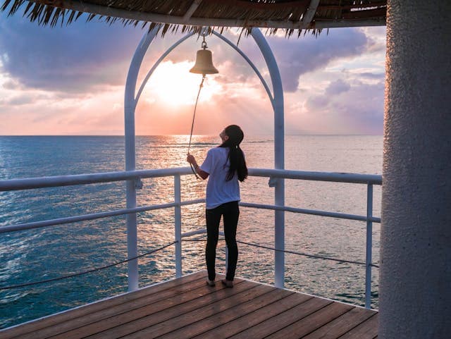 Une femme sonne une cloche au bord de l'océan