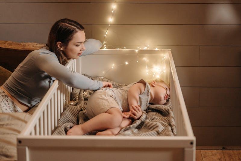 Mère veillant sur son bébé endormi dans une chambre douce — veilleuse pour bébé