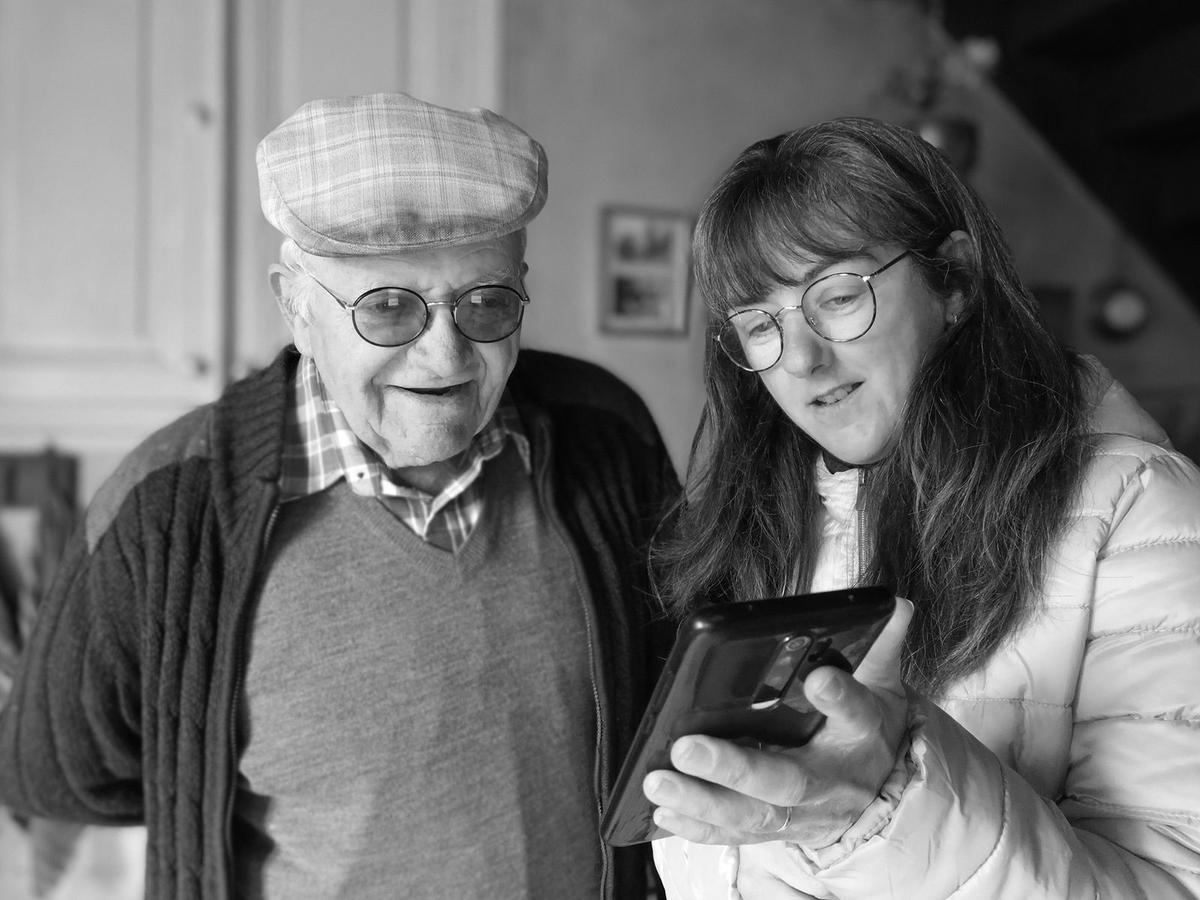 Grand-père qui découvre les photos de la famille sur le smartphone de sa petite-fille
